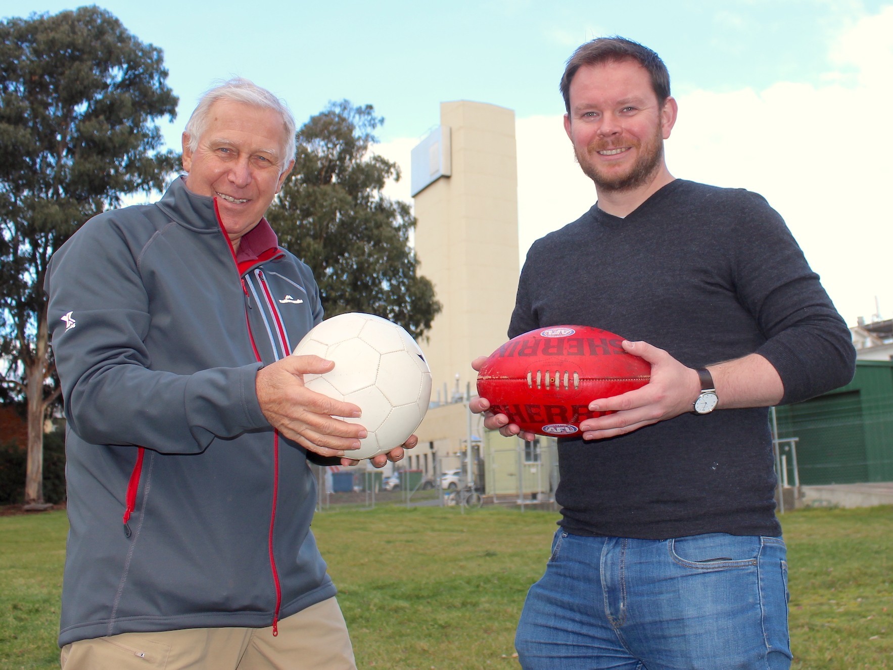 Two mens holding footballs